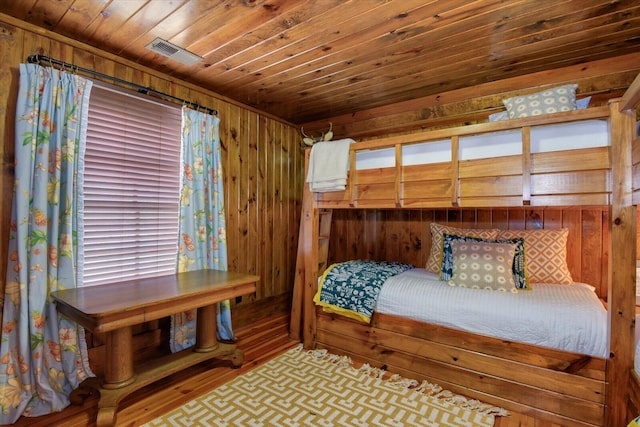 bedroom featuring wooden ceiling, wood walls, visible vents, and wood finished floors