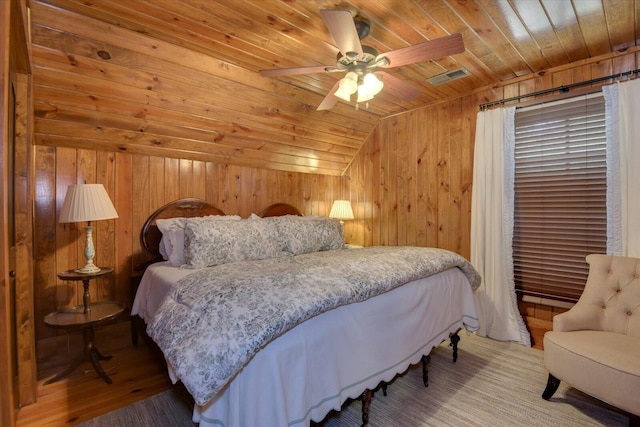 bedroom with visible vents, vaulted ceiling, wooden walls, wood finished floors, and wooden ceiling