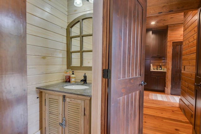 bathroom featuring wooden walls, wood finished floors, and vanity