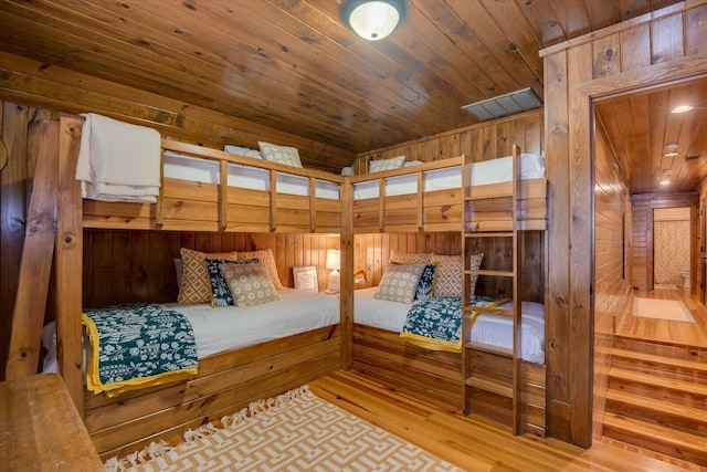 bedroom with wooden ceiling, wooden walls, visible vents, and wood finished floors