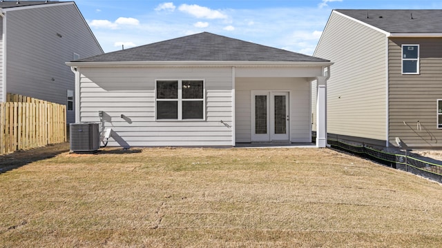 rear view of property with fence, roof with shingles, a yard, and cooling unit