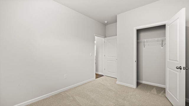 unfurnished bedroom with baseboards, carpet flooring, and a closet