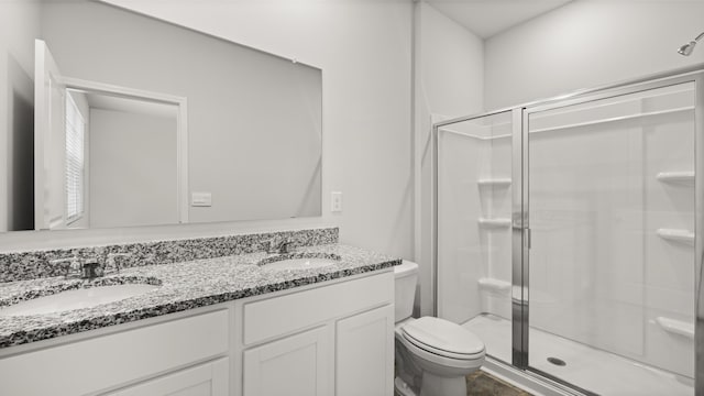 bathroom featuring a stall shower, a sink, double vanity, and toilet