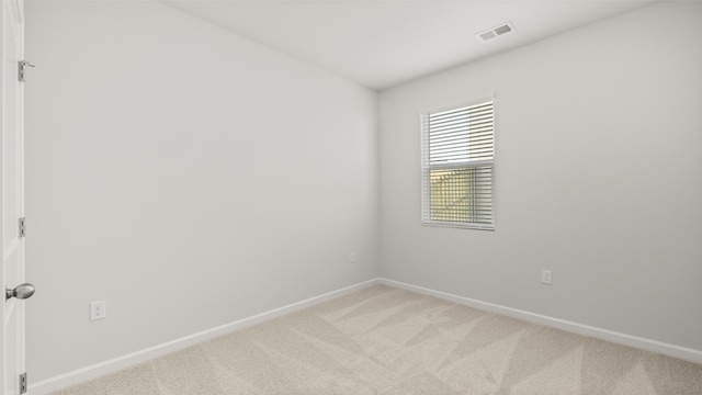 empty room with baseboards, visible vents, and light colored carpet