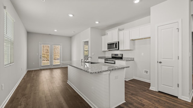 kitchen with dark wood-type flooring, white cabinetry, an island with sink, and stainless steel appliances