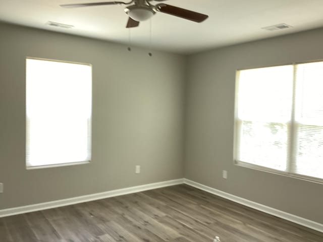 unfurnished room featuring dark wood-type flooring, ceiling fan, and a healthy amount of sunlight