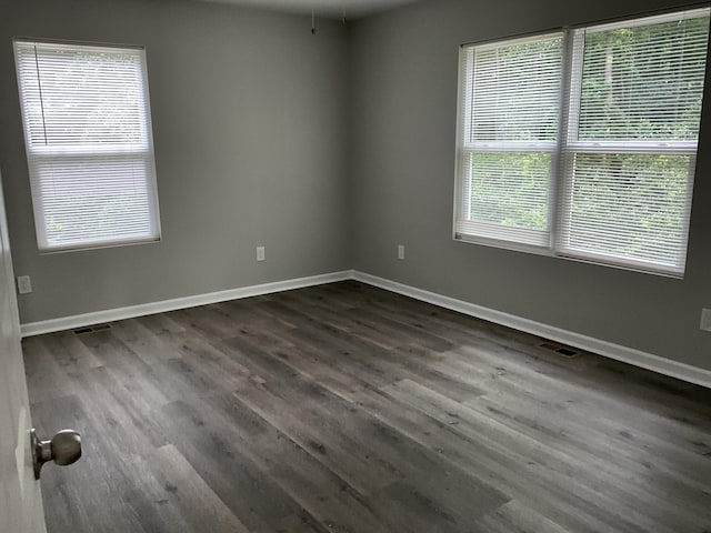 spare room with a wealth of natural light and dark wood-type flooring