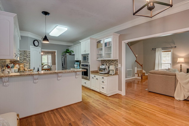 207 Oleander Trl, Evans, GA 30809 - kitchen featuring stainless steel appliances, a breakfast bar area, backsplash, a peninsula, and glass insert cabinets