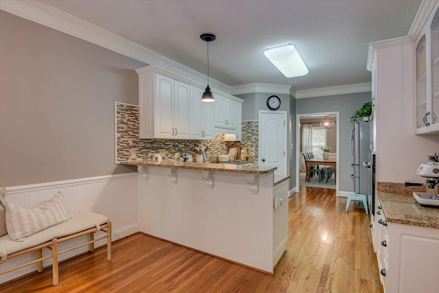 207 Oleander Trl, Evans, GA 30809 - kitchen featuring a peninsula, a breakfast bar, backsplash, light stone counters, and light wood-style floors