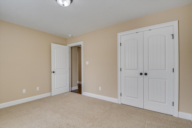 unfurnished bedroom with carpet floors, a closet, and baseboards