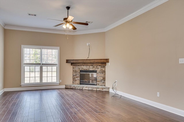 unfurnished living room featuring a stone fireplace, wood finished floors, visible vents, baseboards, and ornamental molding