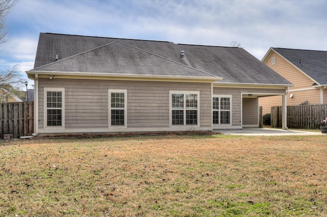 back of property with a yard, roof with shingles, fence, and a patio