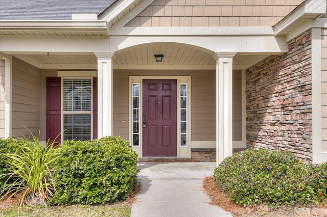 entrance to property with roof with shingles and brick siding