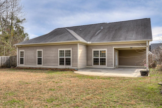 back of house featuring a shingled roof, a patio, fence, and a lawn