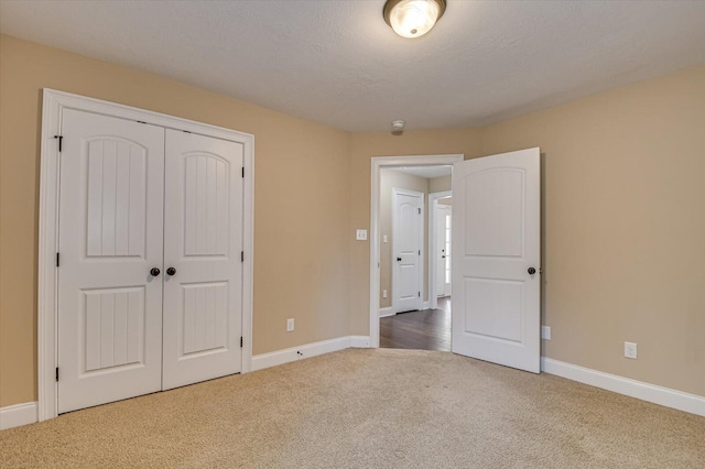 unfurnished bedroom with a closet, carpet flooring, a textured ceiling, and baseboards