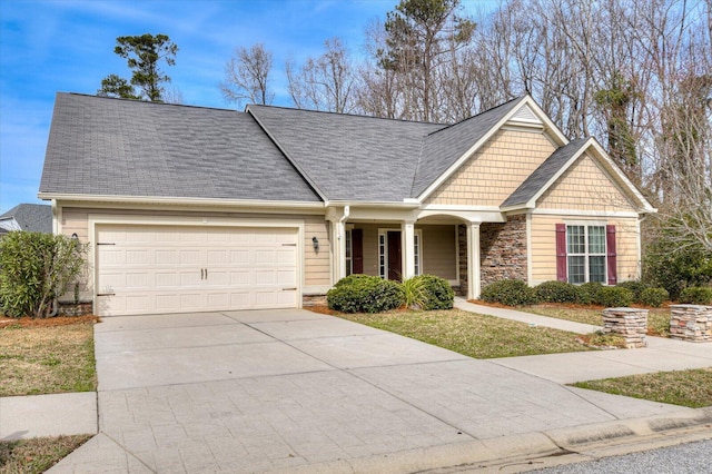 view of front of property with driveway, stone siding, roof with shingles, and an attached garage