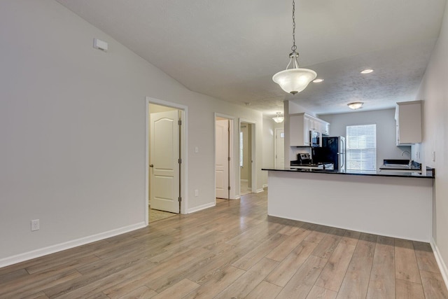 kitchen with white cabinetry, light wood-type flooring, hanging light fixtures, stainless steel appliances, and a textured ceiling