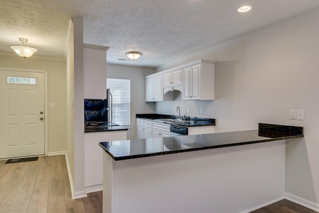 kitchen with sink, dishwasher, light hardwood / wood-style floors, white cabinets, and kitchen peninsula