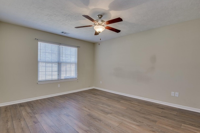 empty room featuring ceiling fan, wood-type flooring, and a textured ceiling