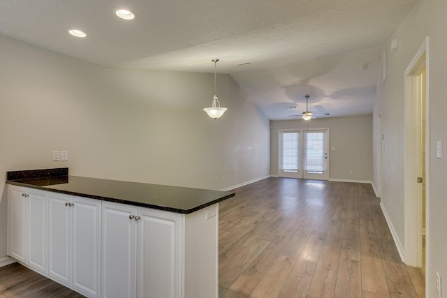 kitchen with vaulted ceiling, pendant lighting, white cabinetry, kitchen peninsula, and light hardwood / wood-style flooring