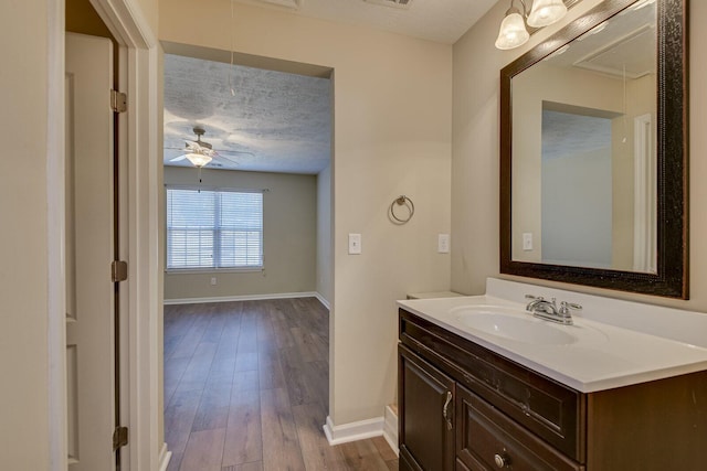 bathroom with ceiling fan, wood-type flooring, vanity, and a textured ceiling