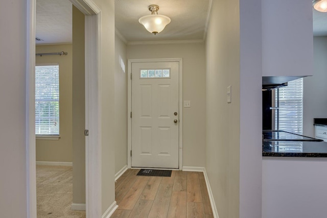 doorway featuring plenty of natural light, ornamental molding, light hardwood / wood-style floors, and a textured ceiling