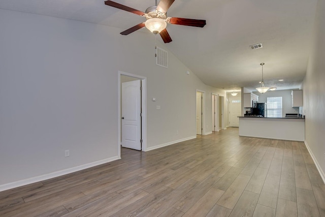 unfurnished living room with ceiling fan, high vaulted ceiling, and light hardwood / wood-style flooring