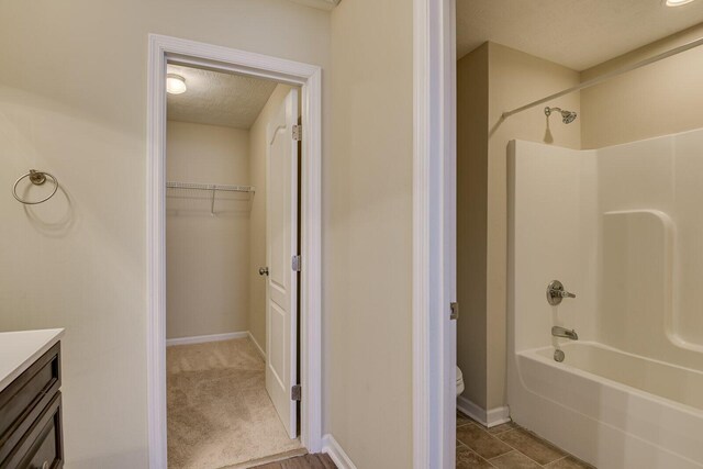 full bathroom with washtub / shower combination, vanity, toilet, and a textured ceiling