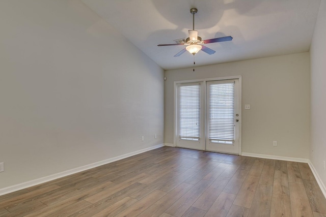 empty room with ceiling fan, vaulted ceiling, and light hardwood / wood-style flooring