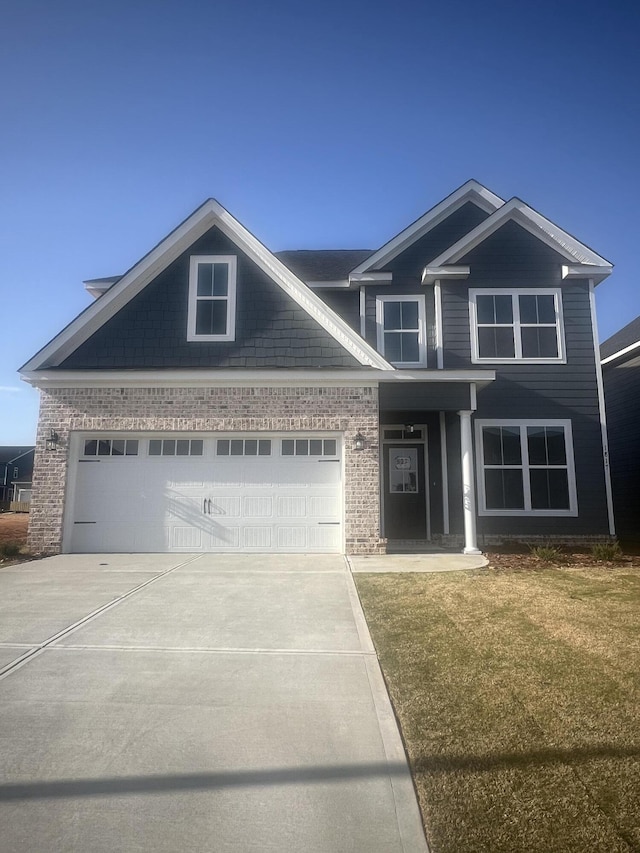 craftsman-style house featuring a front yard, brick siding, and driveway