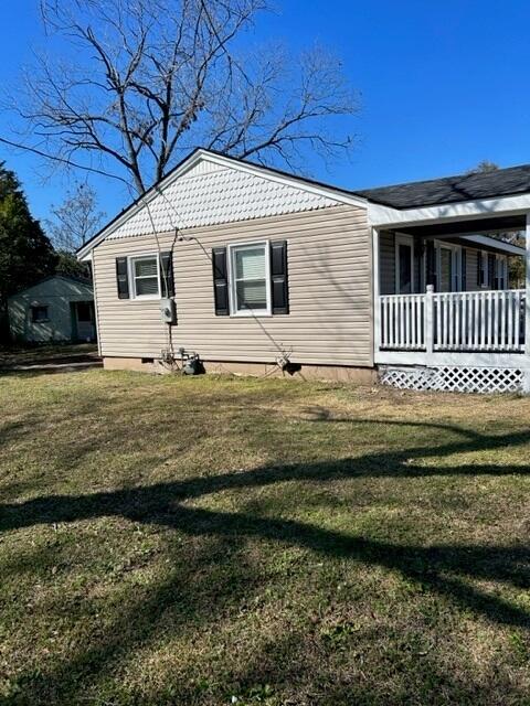 view of side of home with a porch and a lawn