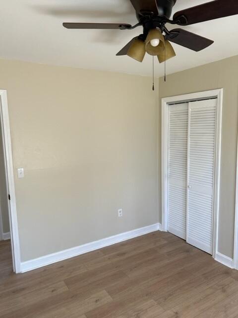 unfurnished bedroom featuring hardwood / wood-style floors, ceiling fan, and a closet