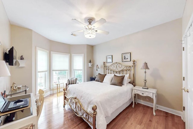 bedroom featuring baseboards, a ceiling fan, visible vents, and light wood-style floors