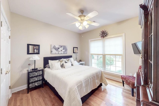 bedroom featuring a ceiling fan, light wood-style flooring, and baseboards