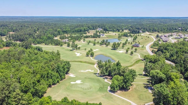 drone / aerial view featuring view of golf course, a forest view, and a water view