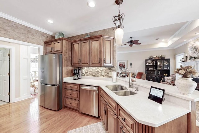 kitchen featuring a peninsula, a sink, light countertops, appliances with stainless steel finishes, and light wood-type flooring