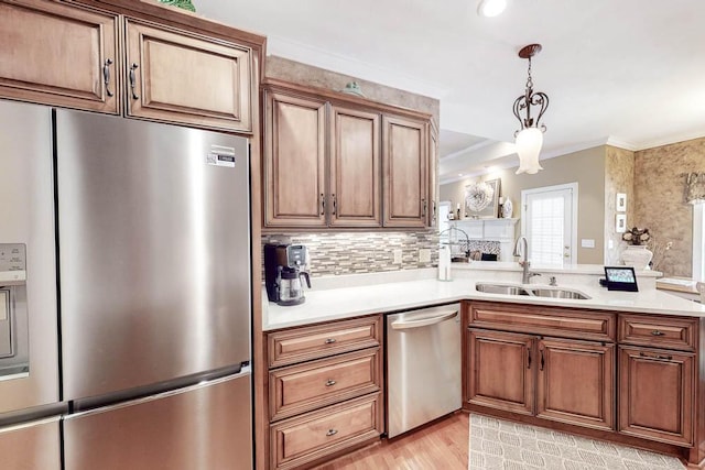 kitchen with stainless steel appliances, a sink, light countertops, light wood finished floors, and crown molding