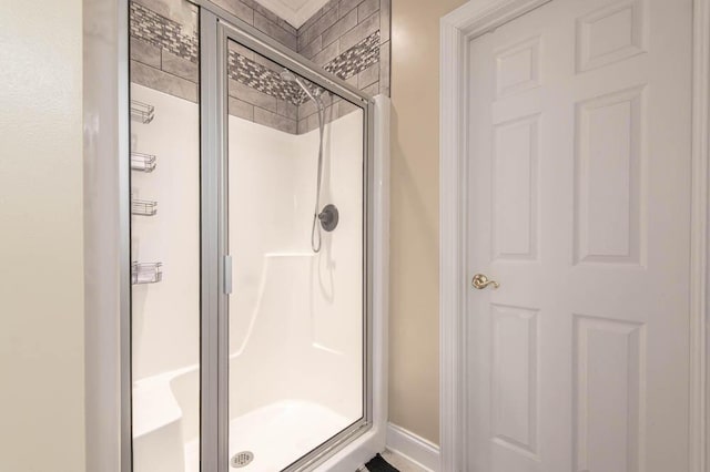 full bathroom with a shower stall and baseboards