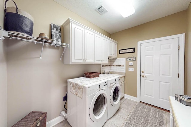 washroom with light tile patterned floors, visible vents, baseboards, independent washer and dryer, and cabinet space