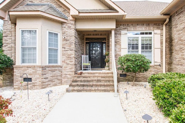 property entrance with roof with shingles, brick siding, and crawl space