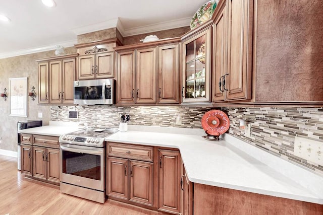 kitchen with light wood-style flooring, light countertops, ornamental molding, appliances with stainless steel finishes, and brown cabinetry