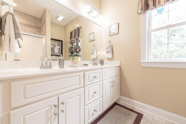 full bath with double vanity, plenty of natural light, baseboards, and tile patterned flooring