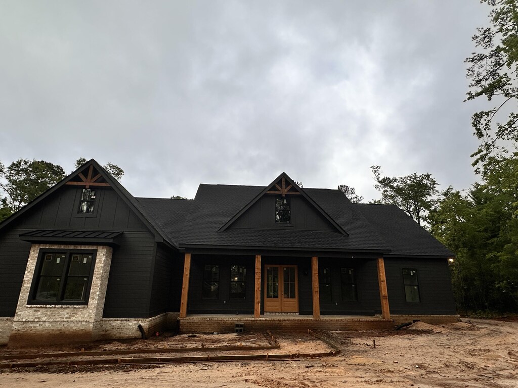 modern farmhouse style home with covered porch, french doors, and board and batten siding