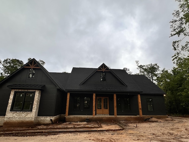 modern farmhouse style home with covered porch, french doors, and board and batten siding