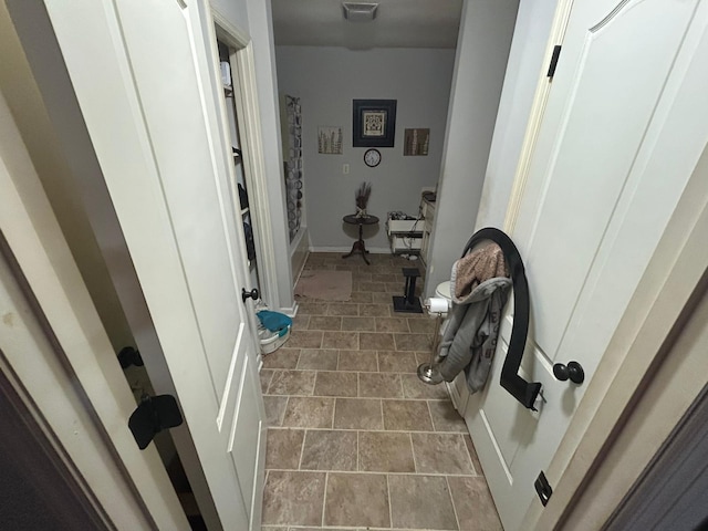 hall featuring baseboards and visible vents