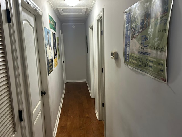 hallway featuring crown molding, attic access, baseboards, dark wood-style floors, and visible vents