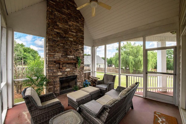 sunroom / solarium featuring ceiling fan, a healthy amount of sunlight, an outdoor stone fireplace, and vaulted ceiling