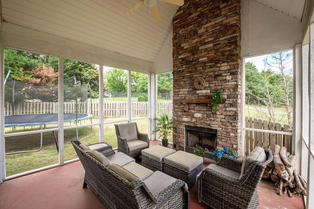 sunroom / solarium featuring lofted ceiling, ceiling fan, and an outdoor stone fireplace