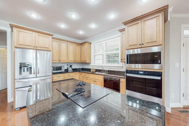 kitchen with light brown cabinets, light hardwood / wood-style flooring, dark stone counters, black appliances, and ornamental molding