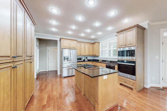 kitchen with stainless steel appliances, light hardwood / wood-style flooring, crown molding, dark stone counters, and a kitchen island